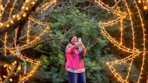 Visitor admiring the lit arch in the Water Garden